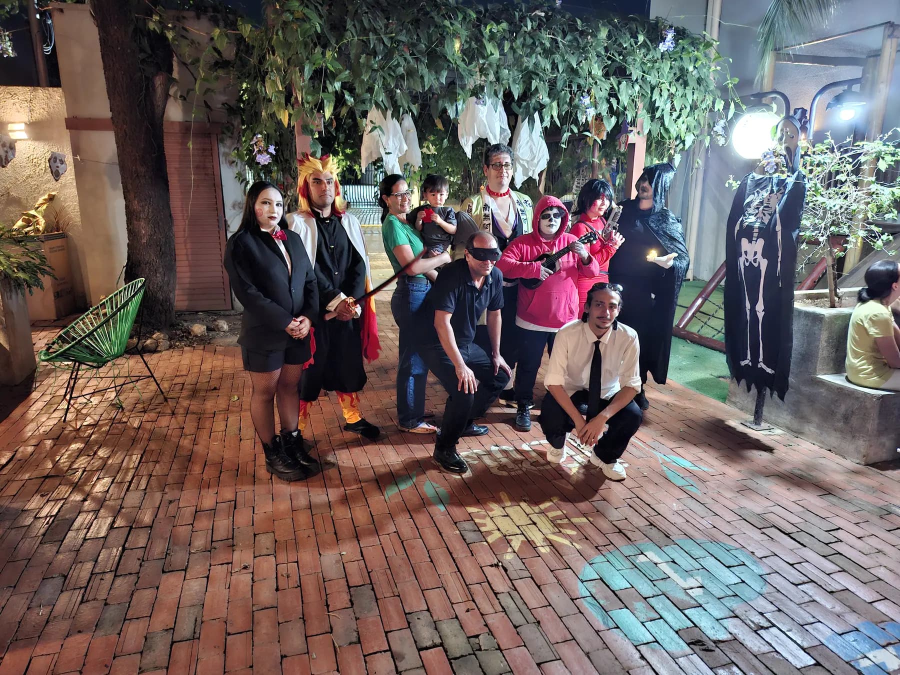 Grupo de participantes com fantasias de personagens e temas de Halloween reunido para uma foto.